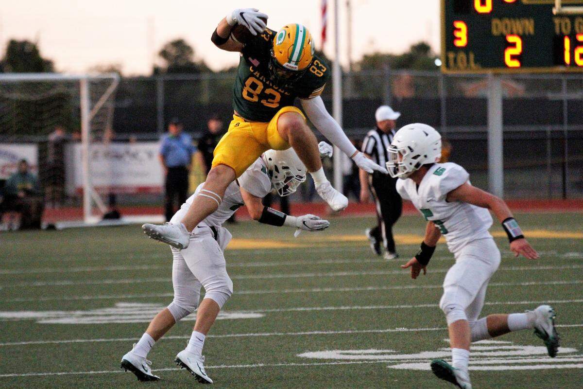 Bishop Carroll senior tight end Clay Cundiff hurdles Derby senior cornerback Dax Benway during the Golden Eagles’ 24-6 loss to Derby on Friday. (Sept. 21, 2018)
