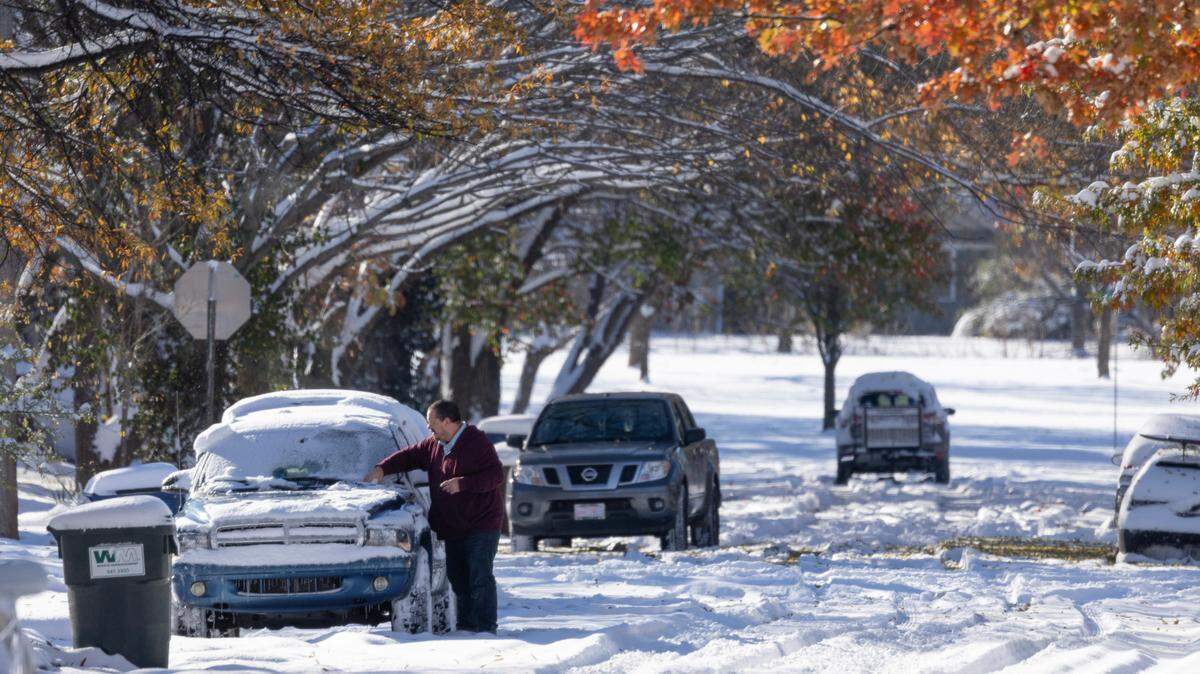 A motorist cleans snow off their car in Wichita in November. Are you required to clear ice and snow from your car before you drive in Kansas?