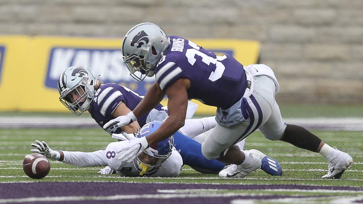 Kansas punt returner Kwamie Lassiter fumbles the punt during the second quarter while Kansas State’s Tyler Burns tries to make the recovery.