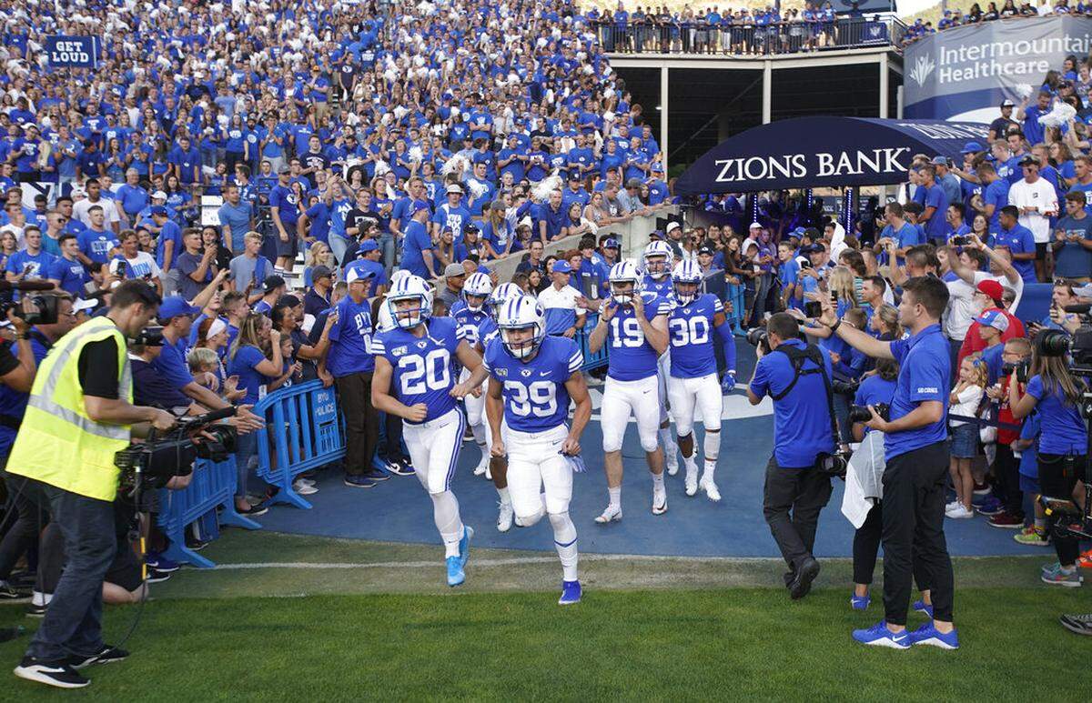 FILE - BYU football players enter the field to warm up for an NCAA college football game against Utah in Provo, Utah, in this Thursday, Aug. 29, 2019, file photo. A deal BYU has made available to its football players could test how much allowing athletes to be compensated by outside companies for name, image and likeness can be used as a competitive advantage. On Thursday, Aug. 12, 2021, BYU announced Built Brands —- a Utah-based company that makes protein-heavy snacks —- will give the opportunity for all 123 members of its football team to be paid to promote its products. (AP Photo/George Frey, File)