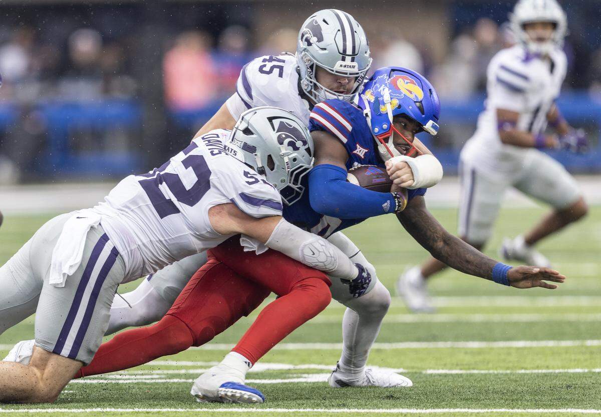 Kansas quarterback Jalon Daniels is brought down by Kansas State defenders Austin Romaine, top, and Ryan Davis during the fourth quarter of their game at David Booth Kansas Memorial Stadium on Saturday, Oct. 25, 2025.