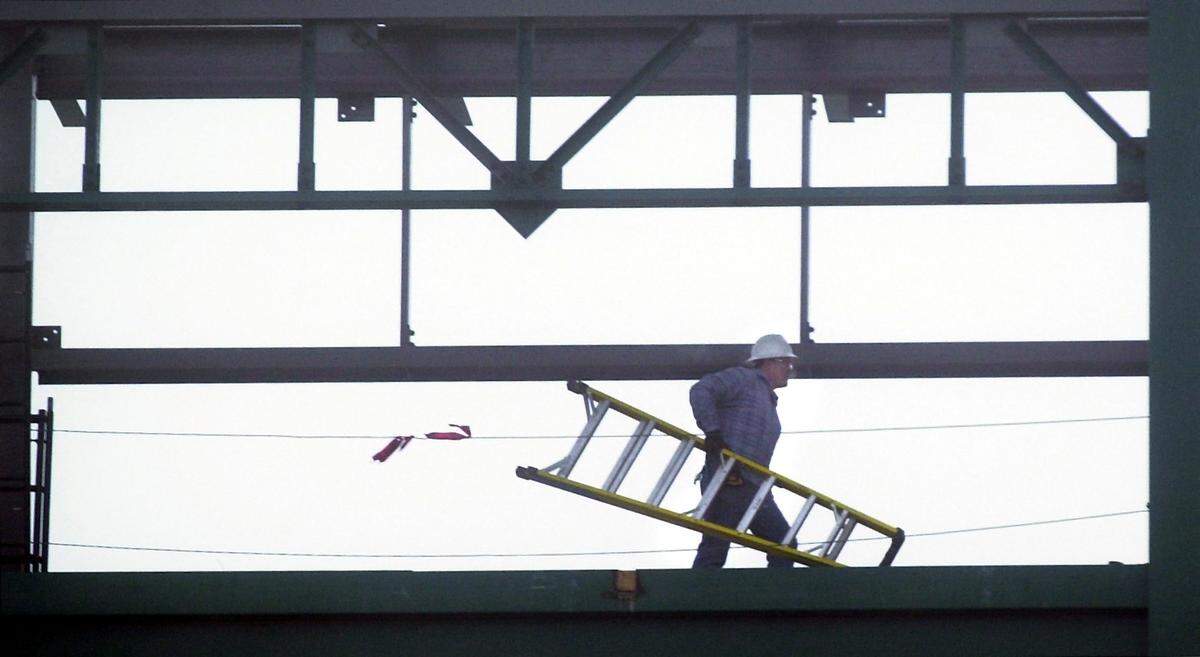 An Eby Construction employee carries a ladder through the fog at the new grandstands the company built at Wichita State University’s Eck Stadium.