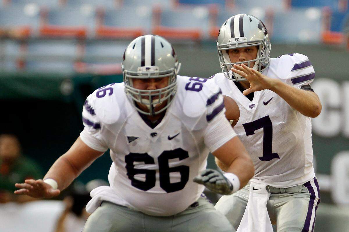 FILE - In this Sept. 24, 2011, file photo, Kansas State’s B.J. Finney (66) snaps the ball to quarterback Collin Klein (7) during the first half of an NCAA college football game against Miami in Miami. Klein takes the snaps from Finney, who often is also there at the end of plays to pick up Kansas State’s hard-nosed running quarterback who doesn’t shy away from taking hits to gain yards. The 11th-ranked Wildcats go for their 11th win when they play No. 7 Arkansas in the Cotton Bowl on Friday. (AP Photo/J Pat Carter, File)