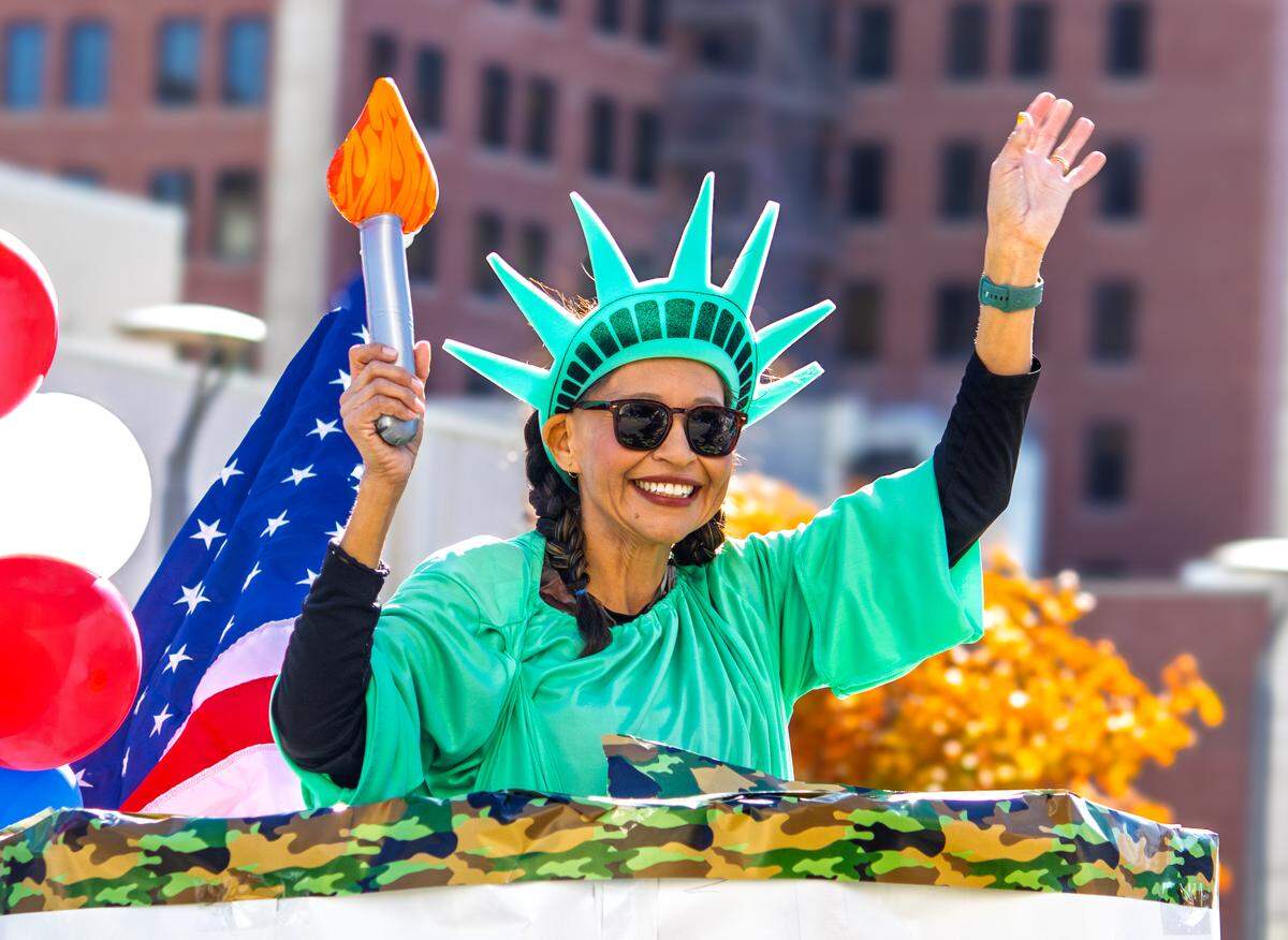 A woman dressed as the Statue of Liberty waves to parade-goers during Wichita’s 2025 Veterans Day on Saturday, Nov. 8. The woman topped the Home Health of Kansas, LLC parade float.