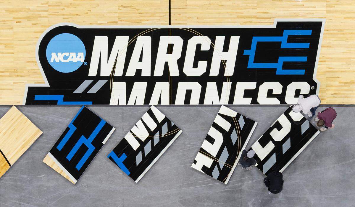 Workers install the court for the upcoming NCAA Tournament at Intrust Bank Arena on Sunday morning. 