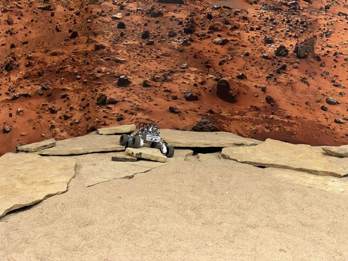 Via remote control from Mission Control, visitors to the Space Discovery Institute can maneuver a rover over a simulated surface of Mars.