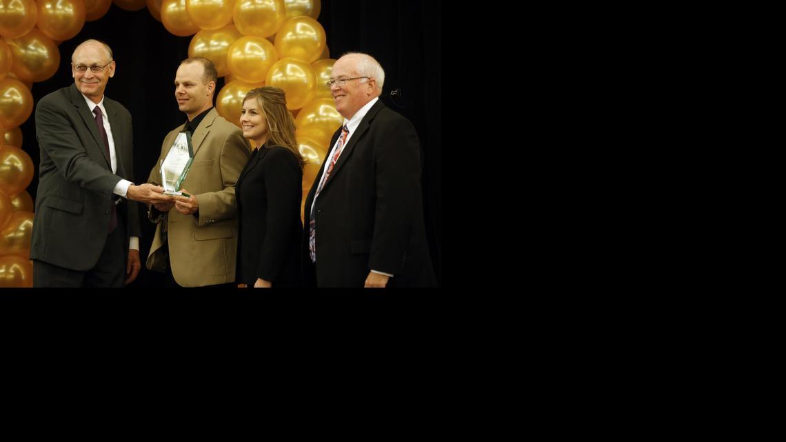 Wayne Chambers, left, chairman of the Wichita Metro Chamber of Commerce, and Gary Plummer, right, president and CEO of the chamber, present Brandon and Tricia Wilson of Icon Structures with the Tier 1 Small Business of the Year Award on Wednesday.  (May 7, 2014)

