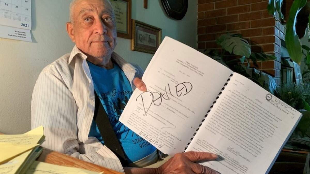 Bernard Bates holds a notebook of documents from the lawsuits he’s been a part of while trying to get his farmland back.
