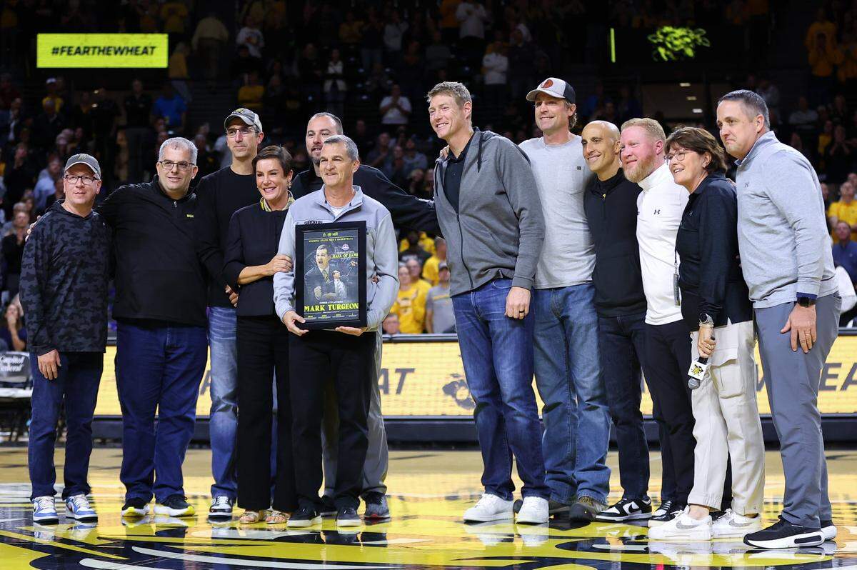Former Wichita State men’s basketball coach Mark Turgeon is surrounded by his wife, Ann, and former players and managers with the Shockers during his time as coach from 2000-07.