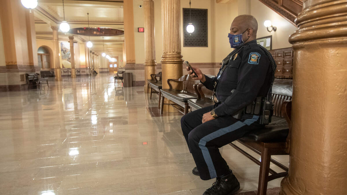 Kansas State Capitol Police Officer Lamont Jackson watches the inauguration of Joe Biden from his phone inside the statehouse on Wednesday. Most government offices in Topeka were closed on Wednesday out of an abundance of caution.