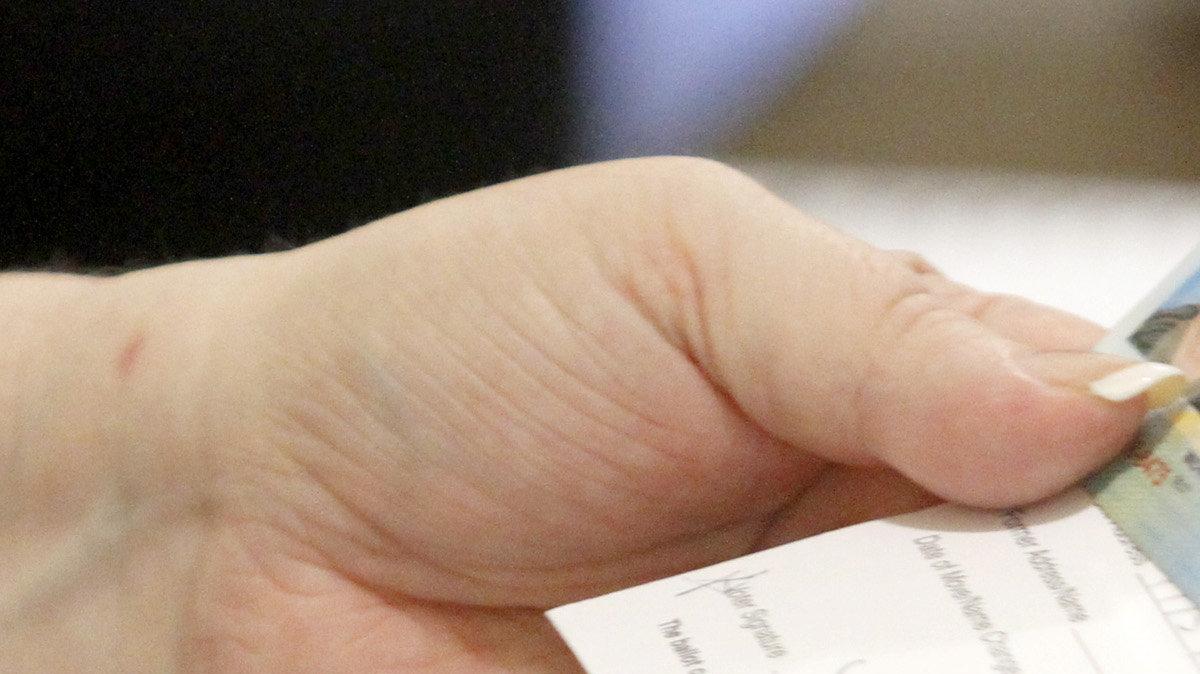A poll worker at St. Andrew's Lutheran Church examines a voter's driver's license. (February 28, 2012)