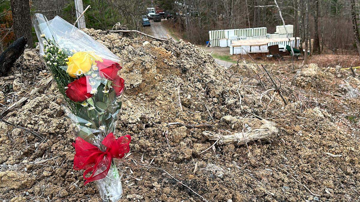 A lone bouquet of flowers marks a desolate makeshift memorial at the end of a driveway at a Bowdoin, Maine, home, where police say four people were killed. A man who police say killed four people in a home and then shot three others randomly on a busy highway had an earlier conviction in Kansas.