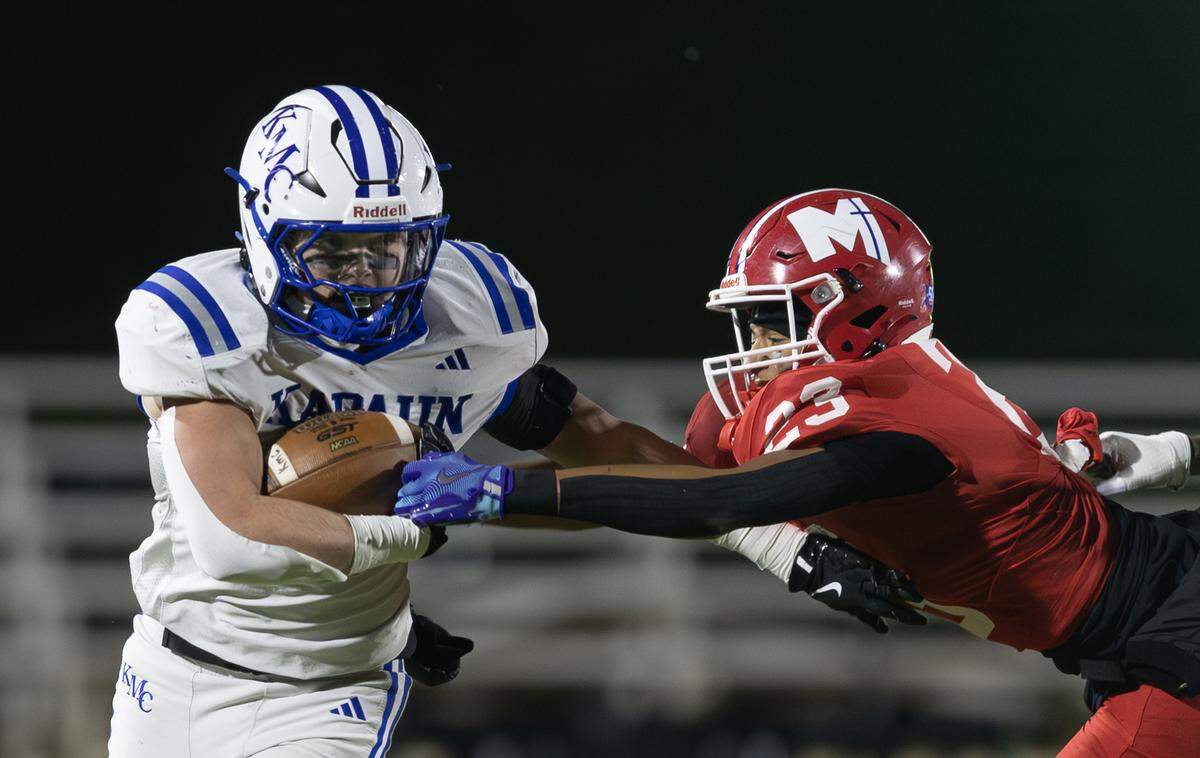 Kapaun running back Kenneth Huff tries to break the tackle of Bishop Miege defender Keenan Poulsen in the second half on Saturday in Emporia. Kapaun defeated Bishop Miege 56-21 to win the 4A state title.