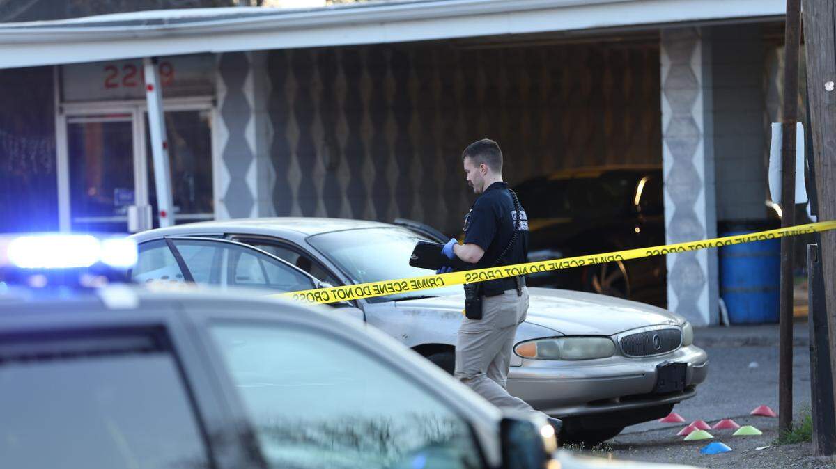 A Wichita officer investigates a fatal parking lot shooting Thursday in the 2200 block of North Grove. The Buick behind the officer has apparent bullet holes in the front windshield. Police also placed cones on the ground around evidence.