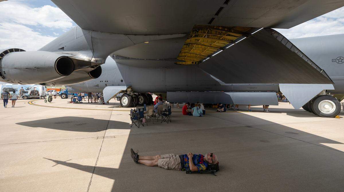 An attendee of Saturday’s airshow at McConnell Air Force Base, seeks relief from the heat under the wing of a B-52 bomber. Over 100 people were treated for heat-related issues at the airshow.