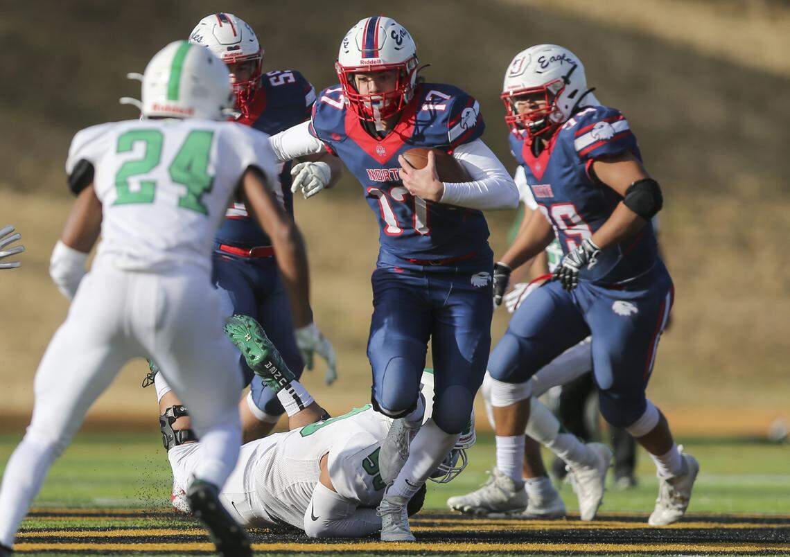 Derby football players sink their teeth into the 6A state championship trophy after defeating Olathe North 63-26 on Saturday in Emporia.