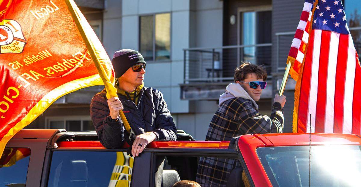 Members of Wichita Firefighters-IAFF Local 135 wave flags while riding in Wichita's Veterans Day parade. Firefighters, as well as an assortment of law enforcement officers, walked in the annual parade.