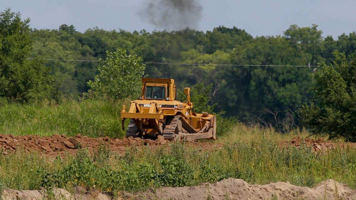 A tractor moves dirt around on land southwest from the corner of 55th and Clifton Tuesday. Homeowners across the street from the dirt and sand-mining operation complained at the Wichita City Council meeting that they had to stay inside during the day because of the dust. The operation was just granted permission to expand.