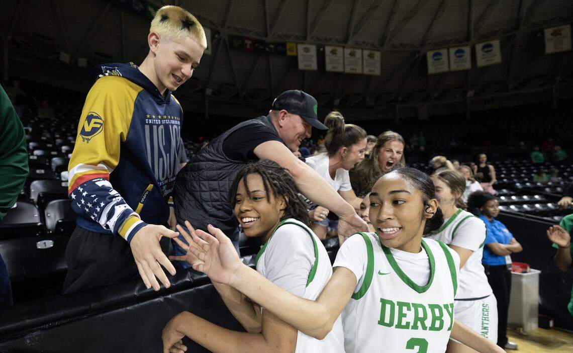 Derby players Macayla Askew, left, and Aysianae Sayarath-Fox celebrate with fans after they defeated Topeka High on Tuesday at the quarterfinals of the 6A basketball tournament at Koch Arena.