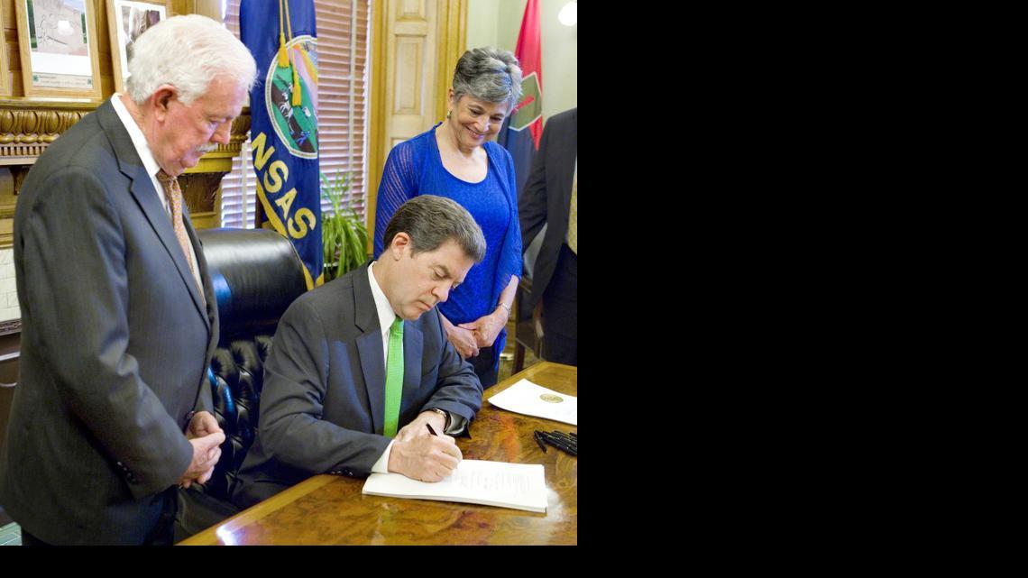 As House Speaker Ray Merrick, R-Stilwell, left and Senate President Susan Wagle, R-Wichita, right watched, Gov. Sam Brownback signed into law Monday afternoon a school funding bill with controversial add-ons. 

