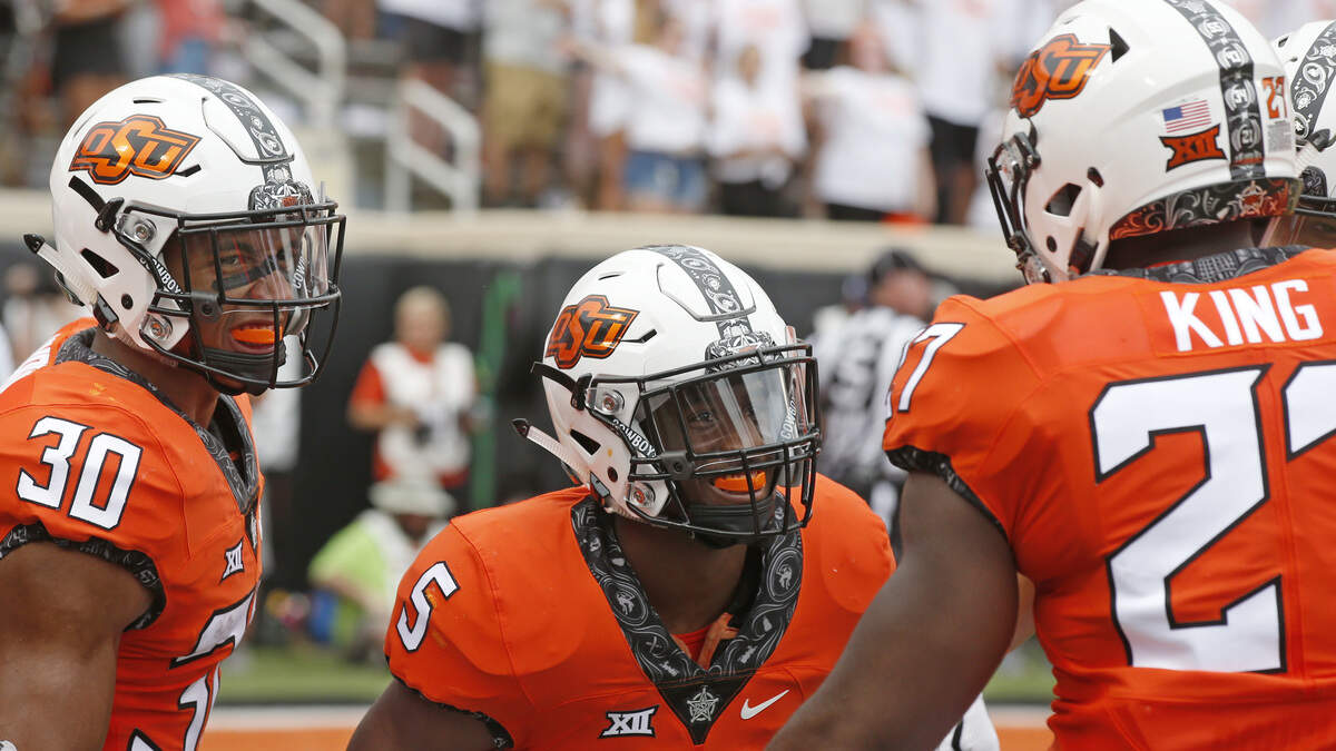 Oklahoma State football players Justice Hill, Chuba Hubbard and J.D. King celebrate their win over Boise State. (AP Photo/Sue Ogrocki)