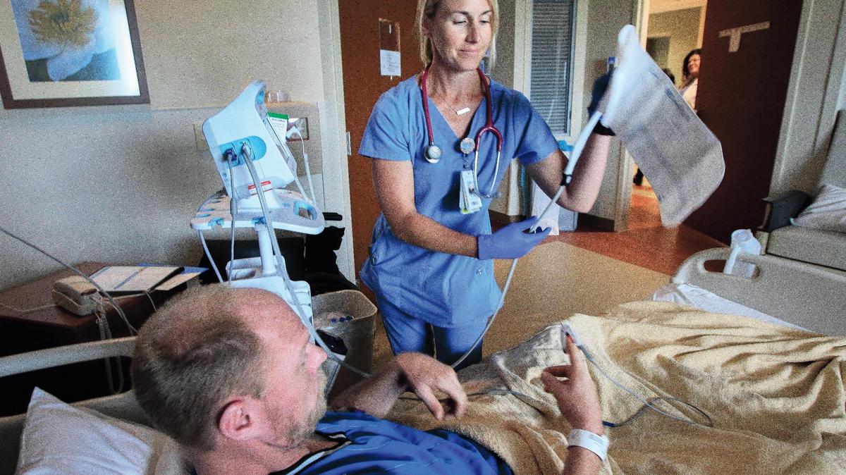 Registered nurse Melissa Stuhlsatz, right, takes Jason Hopper’s blood pressure Wednesday in the medical-surgery unit at Via Christi St. Francis. A new report says the area’s direct health care jobs saw flat growth between 2013 and 2016.  (July 11, 2018)