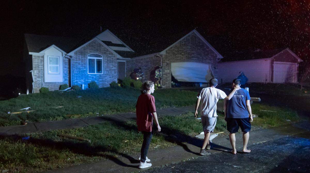 Neighbors watch as firefighters search a home on south Hedgewood Street in Andover on Friday night after a tornado ripped through the area.