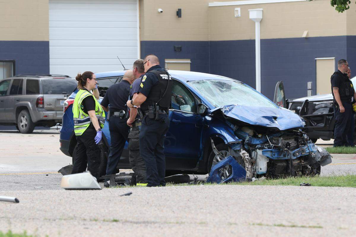 A blue SUV that was involved in a wreck shortly before noon near Downtown Wichita sits in the street being examined by police detectives.