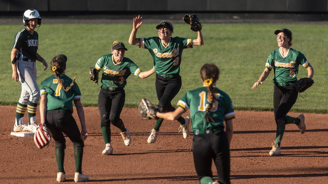 Bishop Carroll’s Kendall Forbes, middle, and the rest of her teammates celebrate after Basehor-Linwood baserunner Britney Hoffman, left, inadvertently kicked a ground ball while running to second, sealing a 4-3 win for Bishop Carroll.