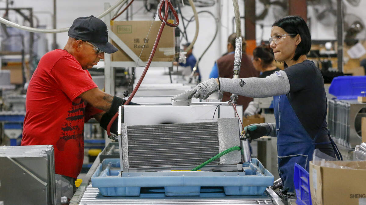 RV Product workers Efran DeLuna, left, and Monica Garcia assemble air-conditioners for recreational vehicles at their plant in north Wichita Wednesday. (July 18, 2018)