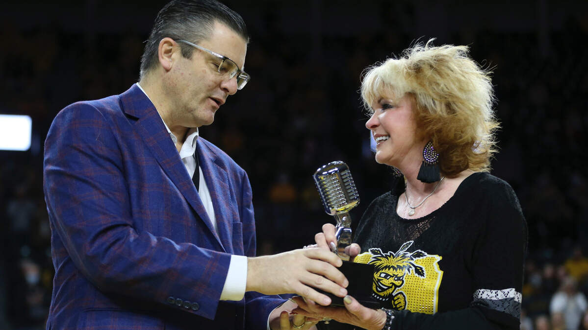 Wichita State athletic director Darron Boatright presents a special microphone to Linda “Fluffy” Hall to honor her husband, Don Hall, who served 36 seasons as the men’s basketball public address announcer before tragically dying in April 2020.
