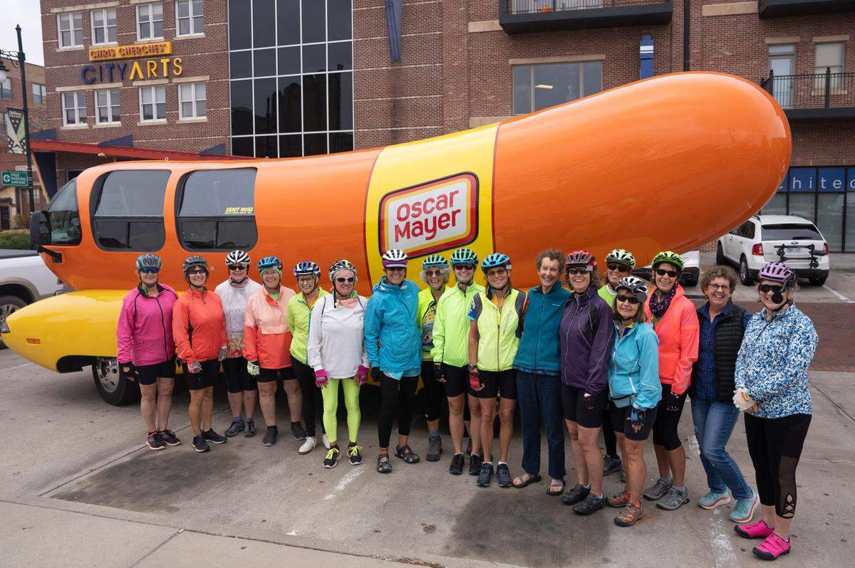 Cyclists with the group WOW (Women of Wednesday) pose in front of the Oscar Meyer Weinermobile while it stopped in Old Town. The Weinermobile will be at various events in Wichita through Nov. 14.