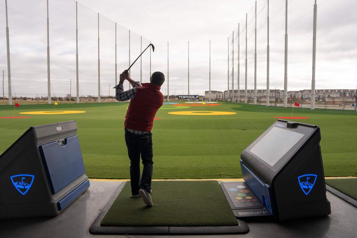 Steven Schulte, director of operations for Topgolf in Wichita, swings a club to explain the different types of games users can play.