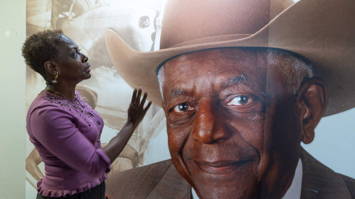 Bonita Gooch, daughter of the late Rip Gooch, looks at an oversized photo of her father at the entrance of the new Rip Gooch Black Aviators Exhibit at the Kansas Aviation Museum. Rip Gooch, a Black aviation pioneer and former Kansas state senator, long advocated for a proper exhibit to honor Black aviators but was unable to see if completed before his death at age 98 in 2021.