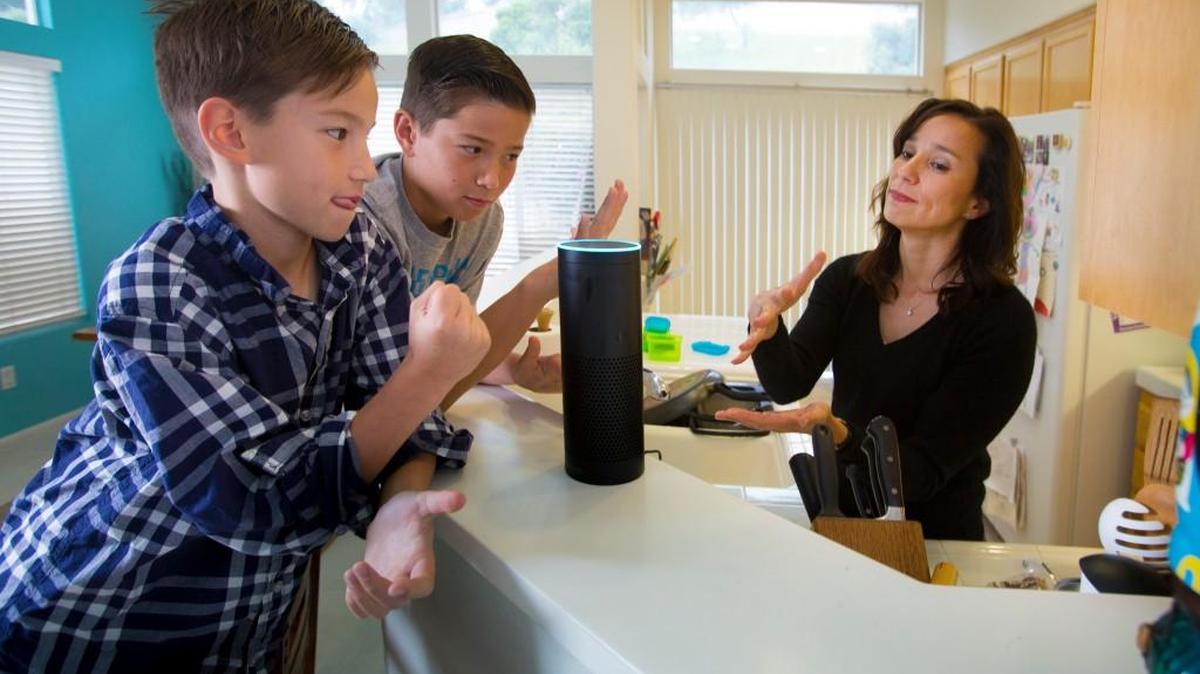 Sutton Philips, left, his brother, Greyson Philips, center, and their mom, Liz Philips, play a game of rock-paper-scissors with Alexa, their Amazon Echo wireless speaker and voice-command personal assistant.