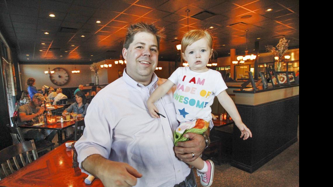 
Bryce Kuhn, owner of Twelve Restaurant & Bar at 12111 W. Maple, poses with his daughter Alyson, 2, at the restaurant on Friday. Kuhn said his experiences as a restaurant owner help him identify with a diner owner in Maine who caught heat after yelling at a crying child. (July 24, 2015)
