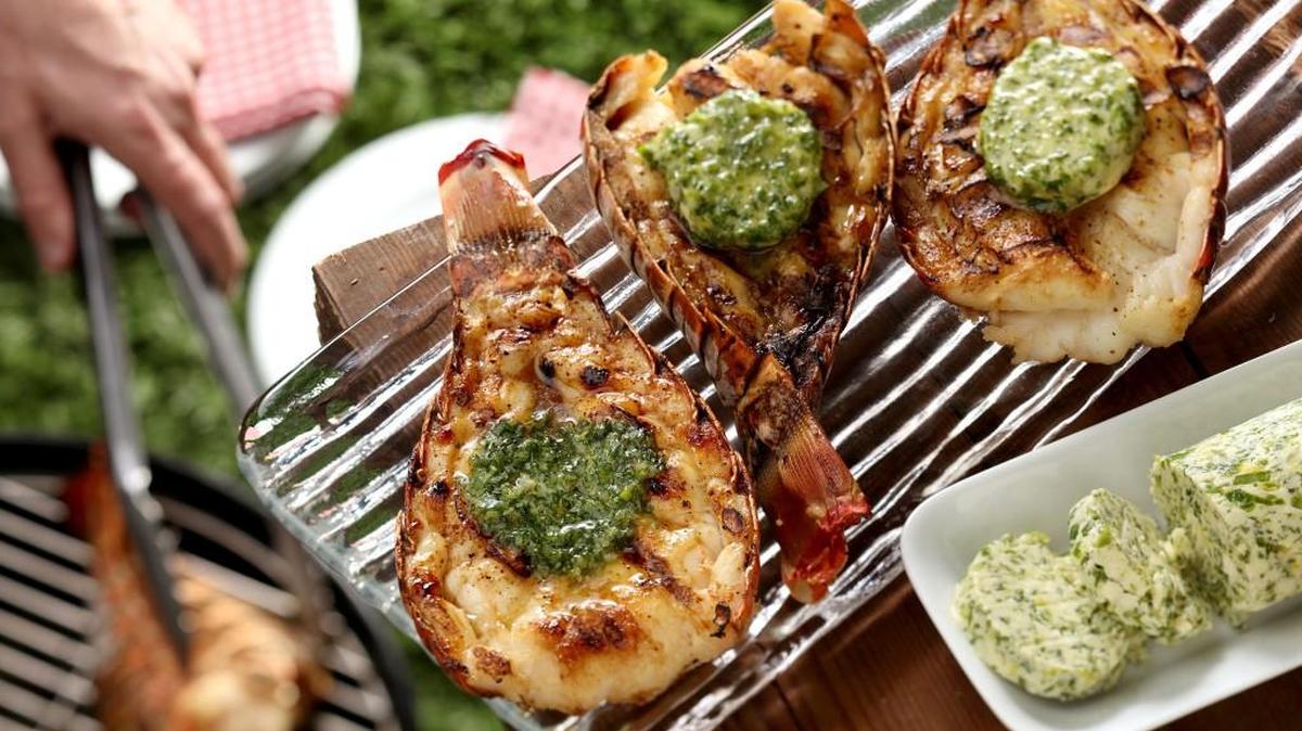 Grilled lobster tails are served with a pat of herbed butter.
