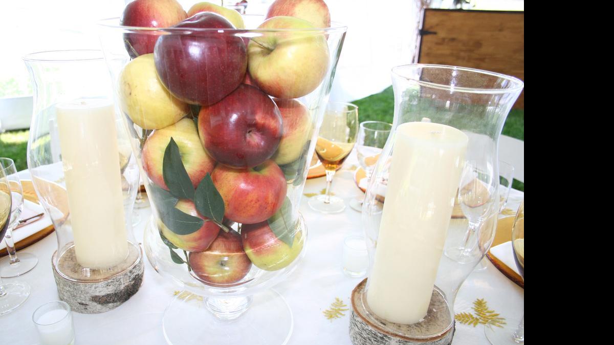 
A jar filled with fresh apples, flanked by candles sitting on birch coins, can make a simple and elegant centerpiece. 
