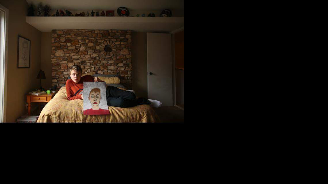 
Devin Wildes holds up a self-portrait he did in chalk in his bedroom – a quiet part of the house with lots of natural light, high ceilings and a neutral color palette. 
