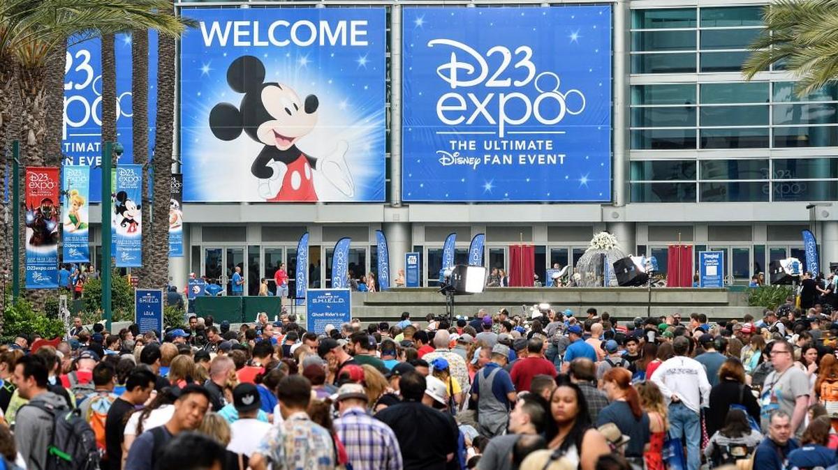 A crowd of people wait to enter the D23 Expo as crews do interviews outside the Anaheim Convention Center in Anaheim, Calif., on Friday, July 14, 2017.