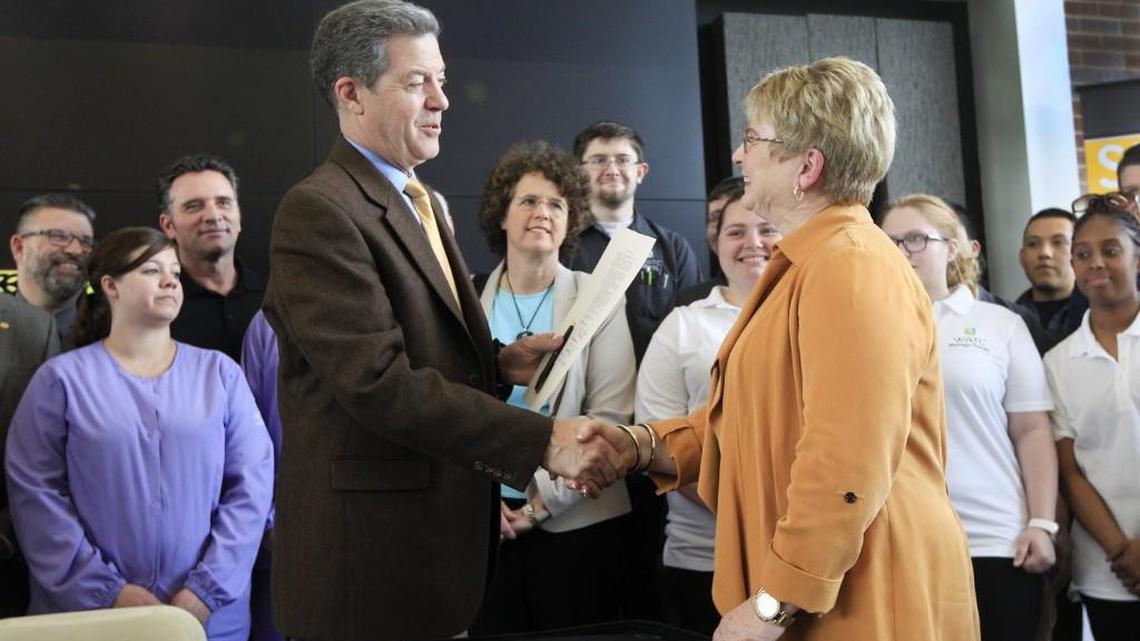 Gov. Sam Brownback, left, shakes hands with WATC president Sheree Utash after signing a bill that officially affiliates Wichita State University with the Wichita Area Technical College, during a ceremony Wednesday at WSU’s Experiential Engineering Building. (April 12, 2017)