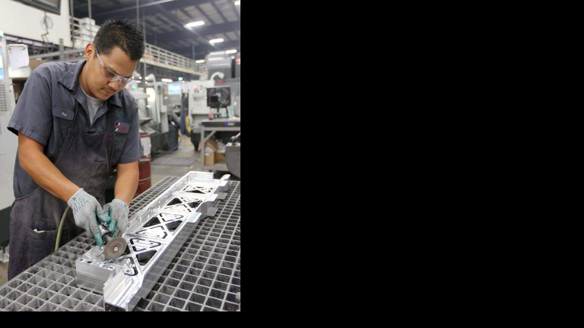 
Paul Perales, a machinist at Cox Machine, removes tabs from a part he made for the 737. (Sept. 23, 2014)
