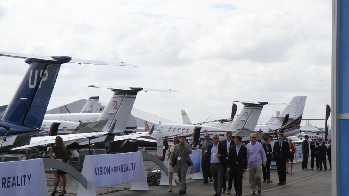 Spectators walk past a cluster of Beechcraft King Airs and Cessna Citation business jets at Orlando (Fla.) Executive Airport during the 2016 National Business Aviation Association Convention.