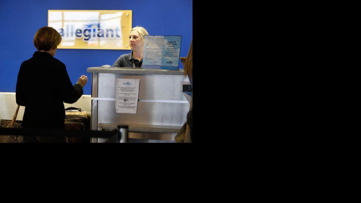 
A traveler checks with a representative at the Allegiant Air counter at Wichita Mid-Continent Airport in February 2011. Starting this month, Allegiant Air is charging passengers $5 for an agent to print a boarding pass at the airport. 
