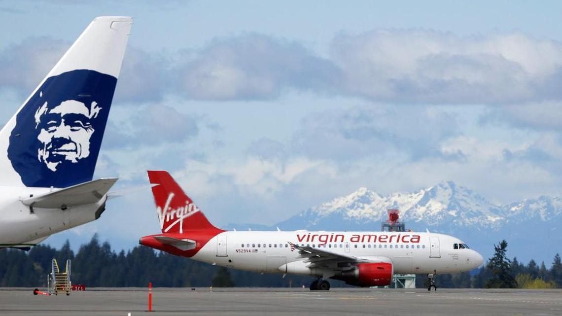 A Virgin America plane taxis past an Alaska Airlines plane waiting at a gate at Seattle-Tacoma International Airport in Seattle in 2016. Alaska announced Wednesday that it will retire the Virgin brand, probably in 2019.