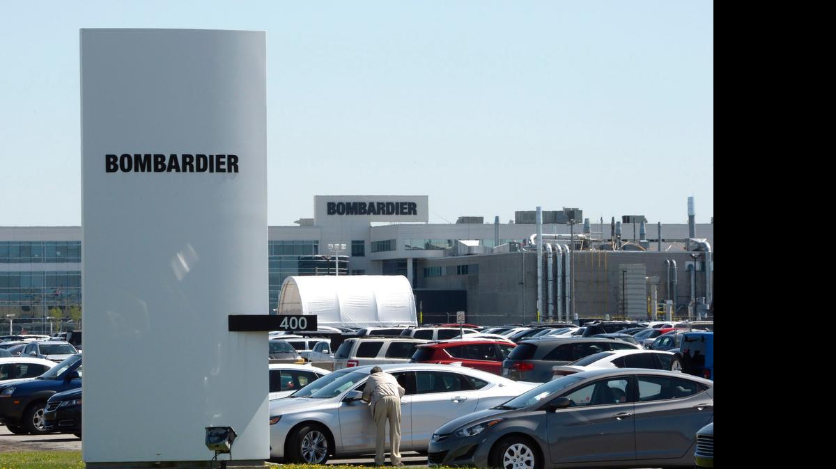 
People walk outside a Bombardier plant in Montreal Thursday, when Bombardier confirmed it will cut more than 1,750 employees in Canada and Northern Ireland over the coming months to adjust for weak demand for some of its business jets.
