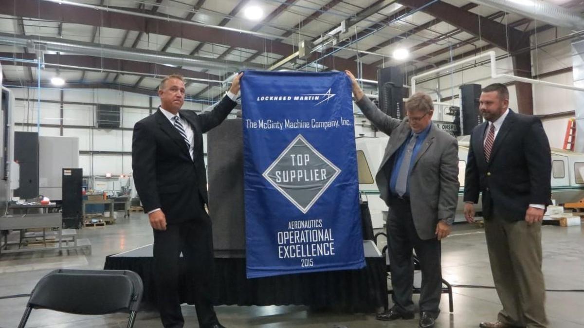From left, Scott Dobbs, Terry Williams and Michael Barker, all of Lockheed Martin in Fort Worth, unfurl a banner they presented Tuesday to McGinty Machine Co. for receiving the defense contractor’s Top 25 Supplier award for 2015.