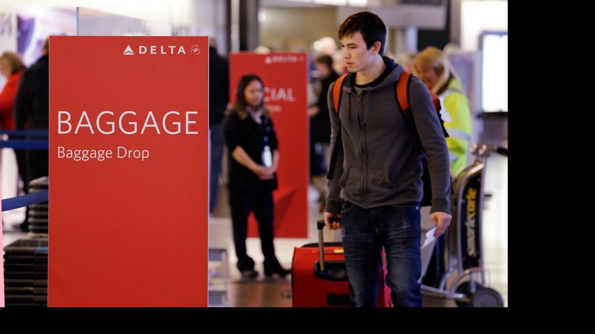 
Travelers walk toward the baggage drop area for Delta airlines at Seattle-Tacoma International Airport in SeaTac, Wash. This summer travel season, Delta plans to preload carry-on bags above passengers’ seats on some flights. 
