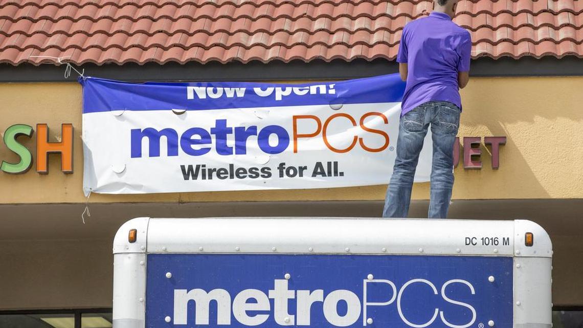 MetroPCS employees put up their new sign in July as they take over the old Fresh Florist space in College Hill Plaza.