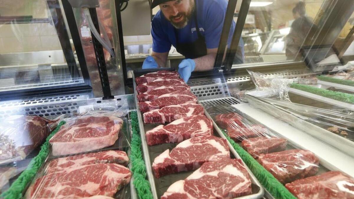 Brian Harpel, a meat cutter with Yoder Meats on West Street, puts fresh rib-eye steaks into the display case Thursday morning. Yoder Meats processes and sells a variety of locally raised meats.